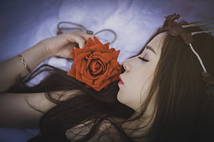 tilt lens photography of brown haired female holding  orange artificial flower HD wallpaper