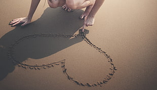 photo of person sketching heart on sand during day time HD wallpaper