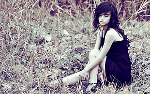 low-light photo of girl in black dress sitting on ground