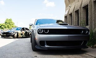 silver Dodge Challenger parked beside gray concrete building