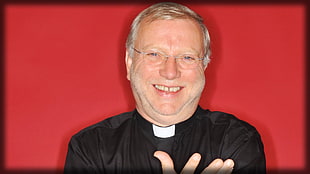 man wearing black priest robe in red background