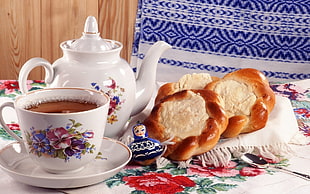 kettle beside teapot with saucer and baked bread on table