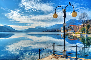 photography of post lamp near body of water during daytime