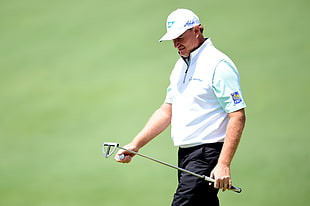 man wearing white shirt holding golf club and ball