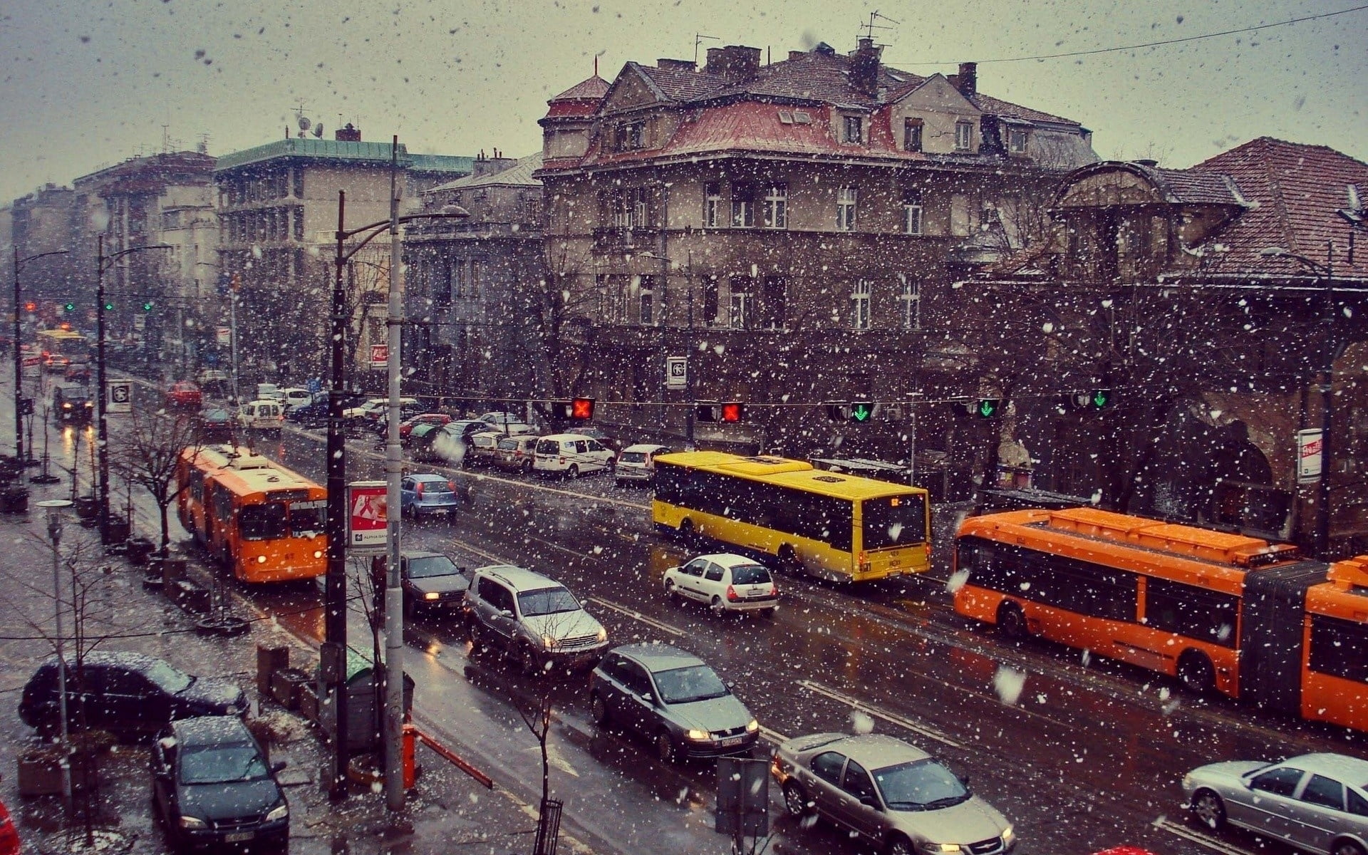 photo of vehicles on road under rain near brown concrete buildings