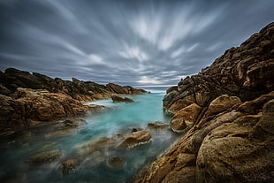 river surrounded by brown rock formation under cloudy sky