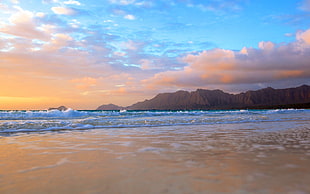 body of water with mountain on the background during sun set