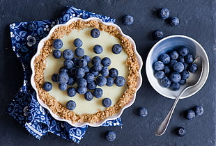 scalloped edge white bowl filled by blueberries with cream