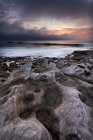 photo of gray and brown rocks near body of water during daytime HD wallpaper