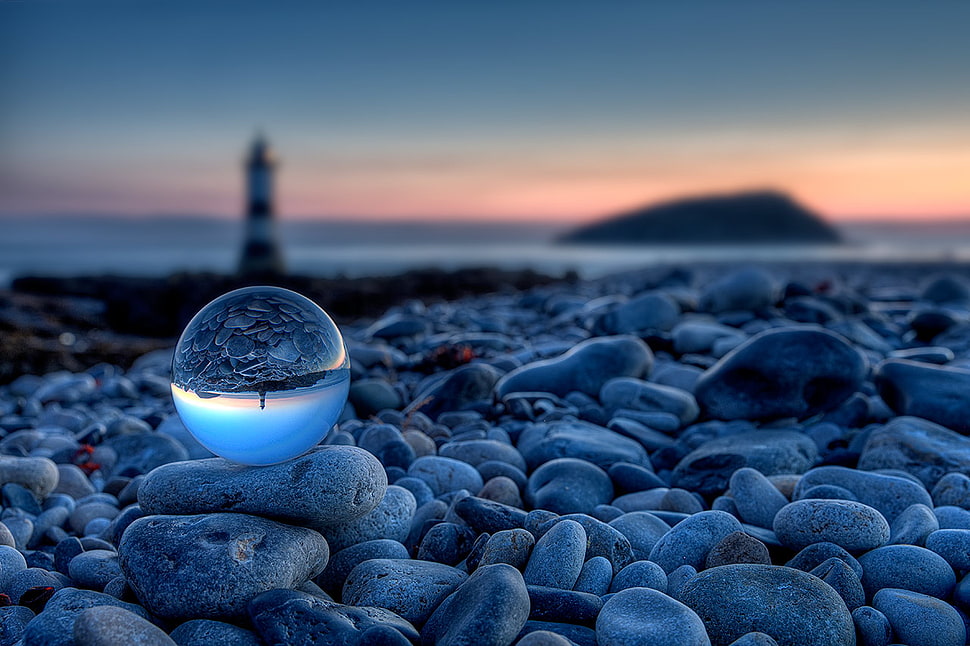 ball on gray stones near lighthouse at golden hour HD wallpaper