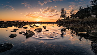 lake surrounded by stones during sunset