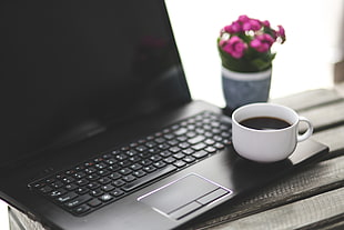 black laptop computer turned off with white ceramic cup