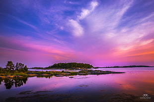 mountain surrounded by body of water with blue and purple sky