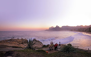 photography of people standing beside sea