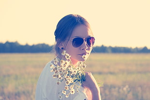 woman in white blouse holding sunflowers