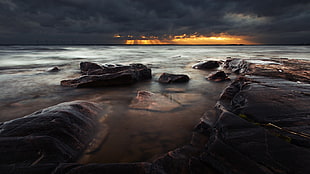 landscape photography of rocks near seashore during golden hour HD wallpaper