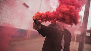 man wearing jacket holding smoke grenade