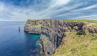 green and gray cliff near body of water HD wallpaper