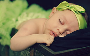 baby wearing green headband sleeping on black textile HD wallpaper