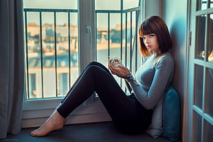 woman in gray long-sleeved shirt sitting near the window HD wallpaper