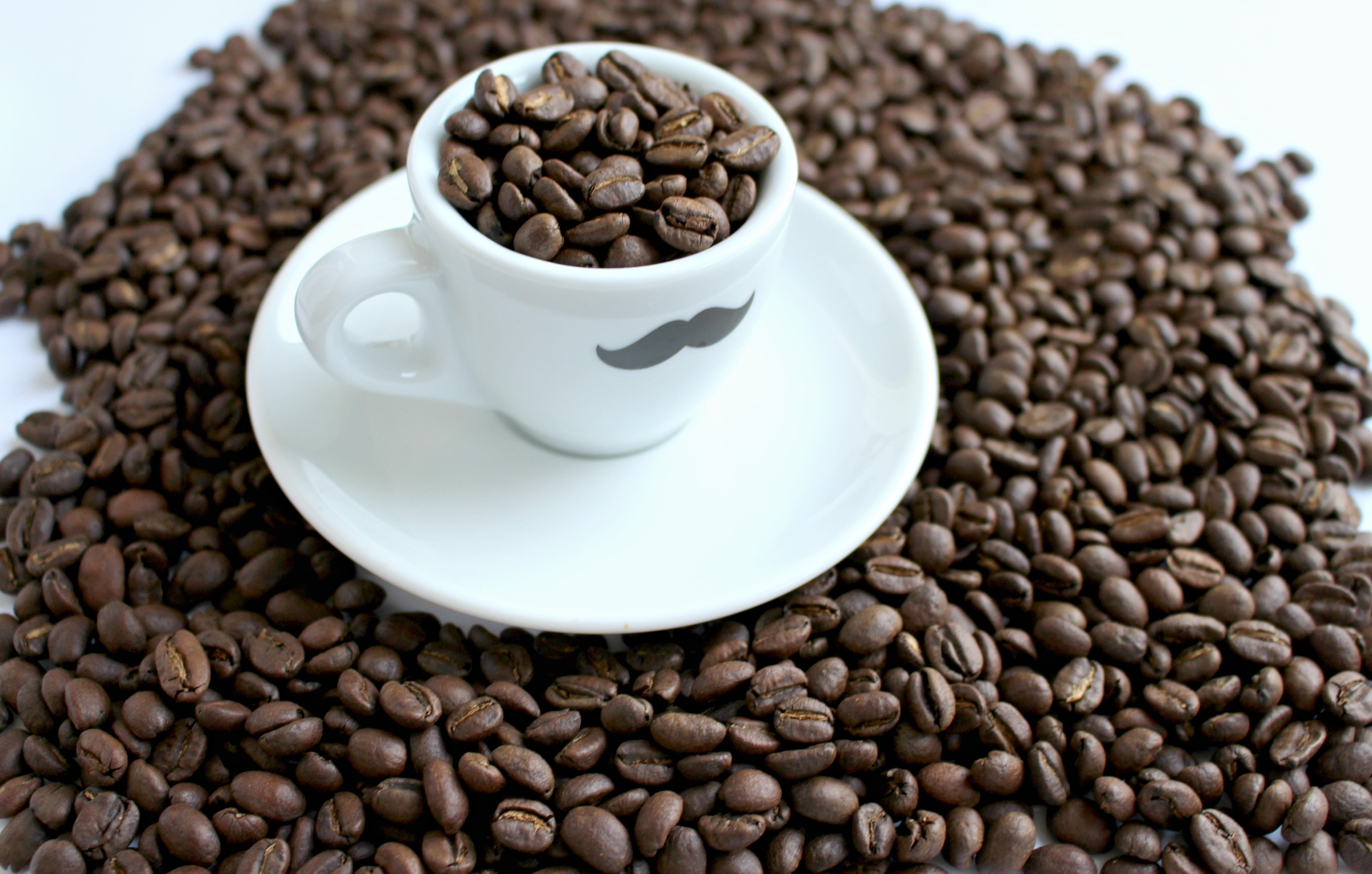 coffee beans with white ceramic mug and saucer