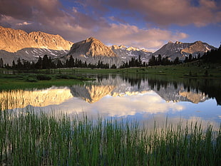 lake in middle of mountain surrounded by grass photography