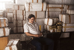 man wearing white polo shirt sitting near boxes