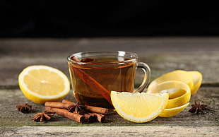 brown liquid filled clear glass cup beside sliced citrus