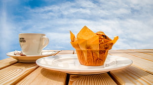 brown cupcake on white ceramic saucer on brown wooden table