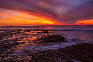 photo of seashore with black boulders during golden hour