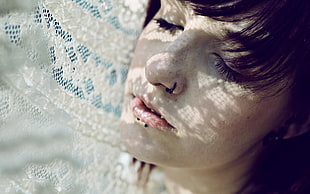 woman with closed eyes under white lace textile