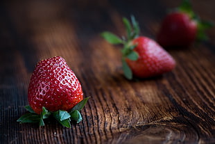 close up photography of red strawberry on brown wooden surface HD wallpaper