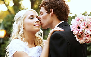 selective focus photography of man kissing woman's cheek
