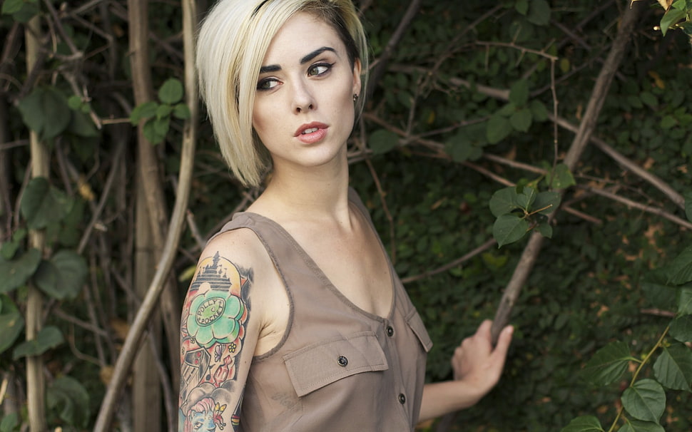 blonde haired female in brown sleeveless top holding tree branch during daytime HD wallpaper