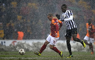 men playing soccer on green grass field during rainy daytime HD wallpaper