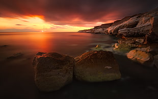 time-lapse photography of cliff beside ocean during golden hour HD wallpaper