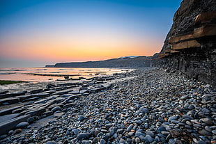 stone fragments near body of water during sunset