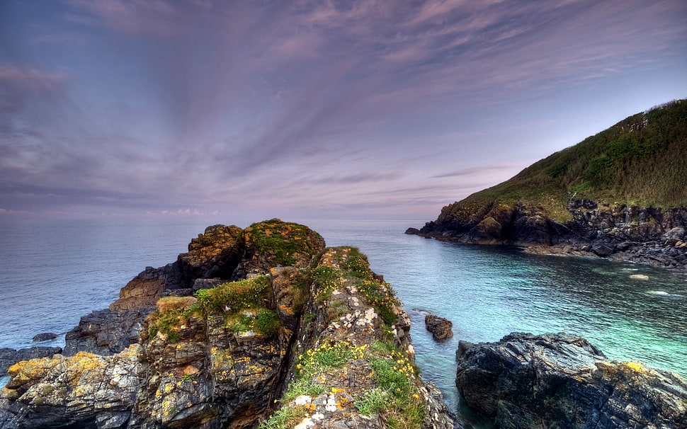 Scenery of green rock formation beside blue body of water during ...