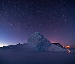 ice burg under black sky full of stars, greenland