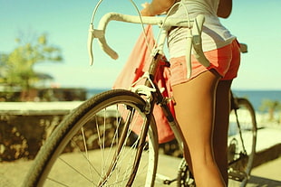 woman wearing pink short shorts holding road bike HD wallpaper