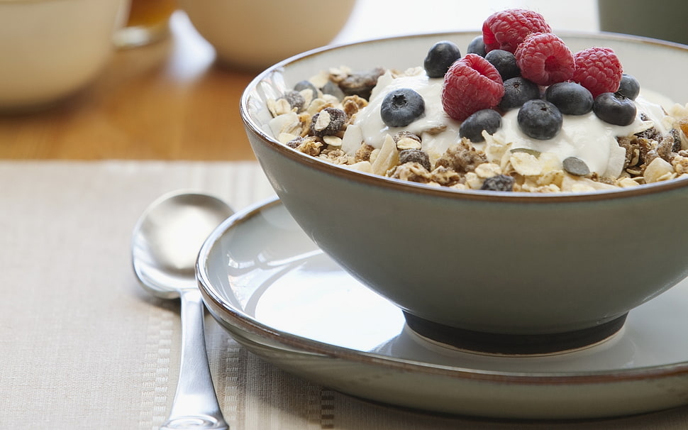 oatmeal with raspberry in white ceramic bowl on plate beside spoon HD wallpaper