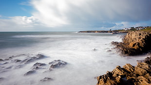 fog on brown rock formations near body of water