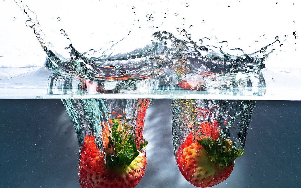 two red submerge strawberry fruits on water HD wallpaper