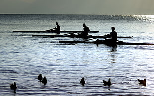 silhouette photo of 3-people sailing during sunset