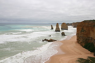 ocean waves hammering rock formation during daytime