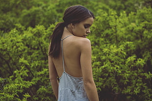 woman wearing gray top standing near green trees