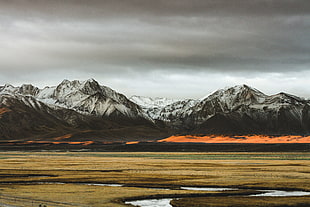 black mountain hill filled with snow under black sky