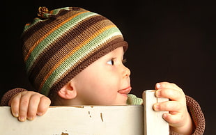 baby wearing brown, orange, and green knit hat HD wallpaper