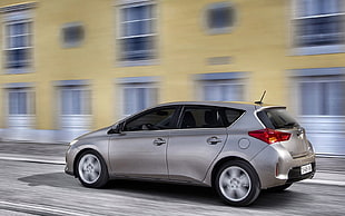 silver 5-door hatchback on road near yellow high-rise building HD wallpaper