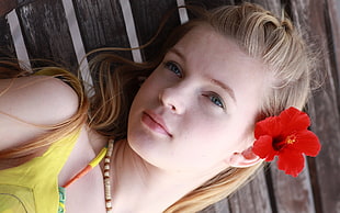 girl in yellow top with red Hibiscus flower